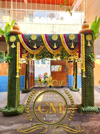A beautiful entrance *chappara* with pillars made of woven coconut leaves and decorated with flower garlands. The CM Events logo shows my brand's commitment to quality.