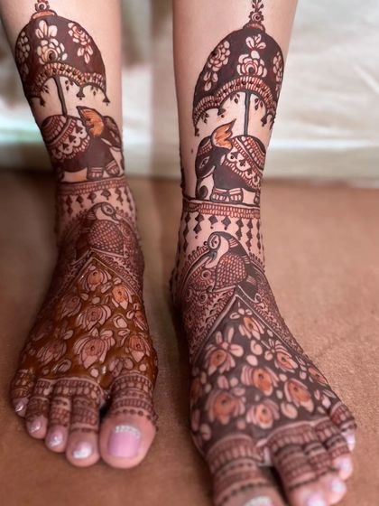 A royal bridal foot design with elephants carrying umbrellas on the leg and intricate floral work on the feet.