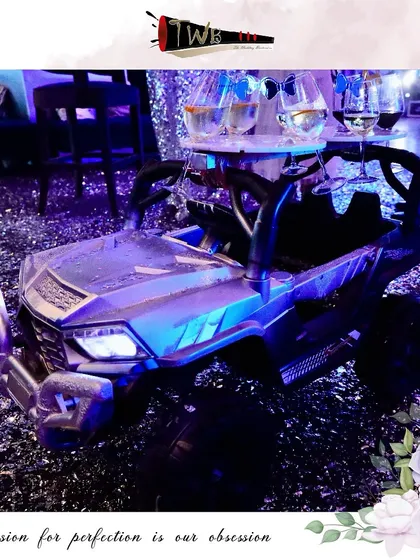 A creative shot serving idea using a remote-controlled toy car, delivering drinks to guests in a fun and unexpected way at a large Christmas party.