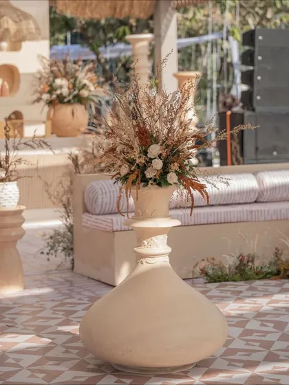 Every detail counts. This large, uniquely shaped vase with dried floral arrangements served as a statement piece, tying the entire rustic Haldi decor together.