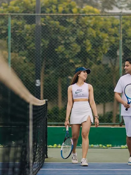 A walk and talk on the tennis court. This candid shot captures the natural interaction and friendship between the couple during their themed pre-wedding shoot.