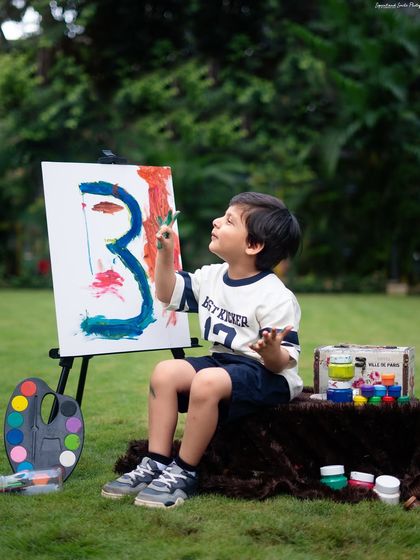 A young artist concentrating on his masterpiece. This "Little Painter" theme, set up in a garden, is a creative way to celebrate a third birthday.