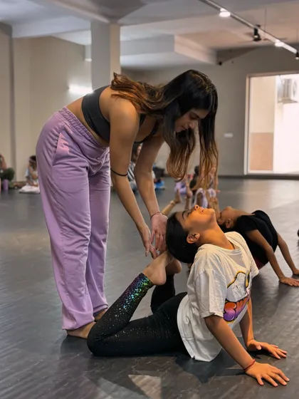 We believe in nurturing every dancer's potential. Here, one of our instructors provides gentle, hands-on guidance to help a young student safely deepen her backbend and improve her flexibility.