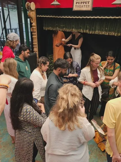 A group of students gathers around a small stage for a hands-on puppet demonstration. These intimate sessions allow for close interaction and give participants a real feel for how the puppets work.