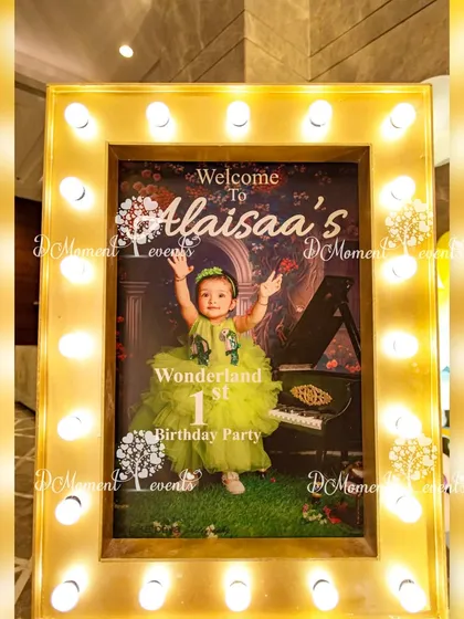 A classic Hollywood-style welcome sign for "Alaisaa's Wonderland 1st Birthday Party." The poster is framed with bright lights, creating a glamorous and exciting entrance for the event.