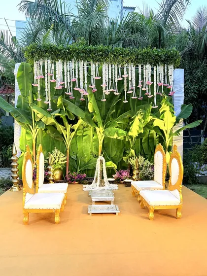 For this South Indian themed ceremony, we created a backdrop using fresh banana leaves and hanging floral strings. The traditional gold and white chairs complete the authentic and elegant look.