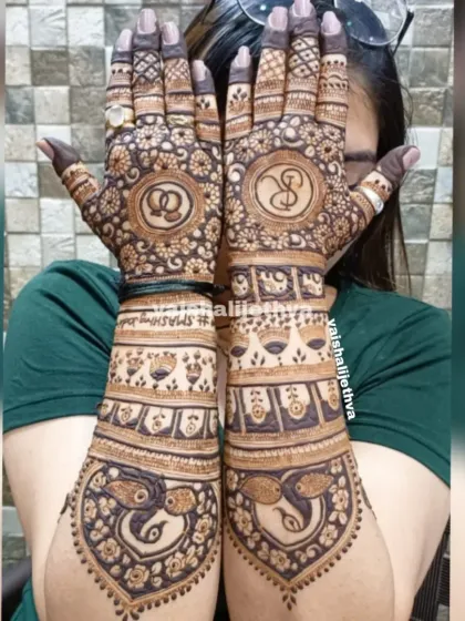 A personalized back-hand design for an engagement. The couple's initials are beautifully incorporated into mandalas, with peacocks at the base.