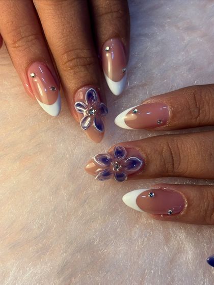 This vacation-ready set features a classic white French manicure on an almond nail shape. We added a pop of fun with 3D purple flowers and tiny silver rhinestones for a bit of sparkle.