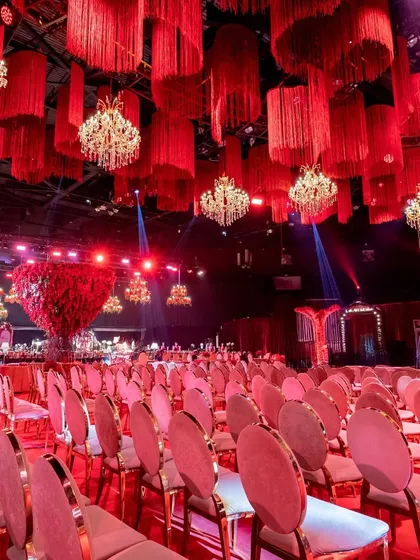 This wide shot shows the extensive seating arrangement, emphasizing the scale of the event and the visual impact of the uniform red chairs and plush sofas.