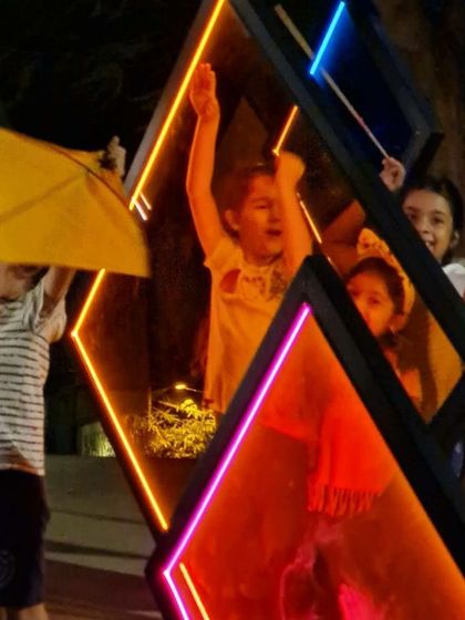 Children playing with glowing sticks inside the 'Family Tree' light installation. Our public art is designed to be playful and engaging for all ages, sparking imagination and creating lasting memories.