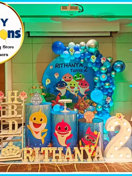 A fun-filled Baby Shark-themed second birthday party. The underwater stage features a large backdrop with the whole shark family, themed plinths, and character cutouts.