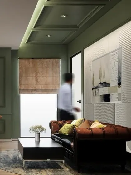 A comfortable seating area within a contemporary office, featuring a classic leather sofa against an olive green paneled wall. This space was designed as a breakout zone for informal meetings or a place for employees to relax.