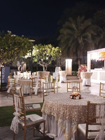 Outdoor seating for a reception, with elegant lace-covered tablecloths and simple floral centerpieces.