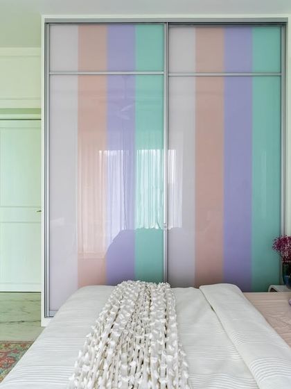 A pastel-striped sliding wardrobe is the focal point of this vibrant bedroom. The soft colors and clean lines add a playful and calming aesthetic to the space.