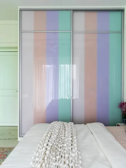 A pastel-striped sliding wardrobe is the focal point of this vibrant bedroom. The soft colors and clean lines add a playful and calming aesthetic to the space.
