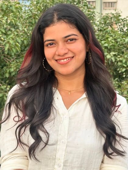 A beautiful smile from a client showing off her subtle red color strands. They blend perfectly with her natural hair, adding a touch of fun and personality to her look.