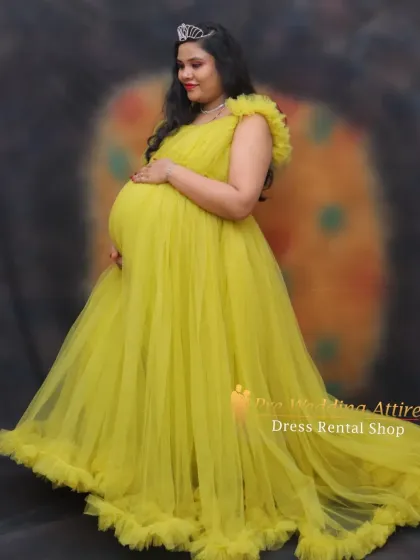 A radiant studio portrait featuring our sunny yellow ruffled gown. The soft tulle and delicate ruffles on the sleeves create a gentle, flattering look that beautifully frames the baby bump.