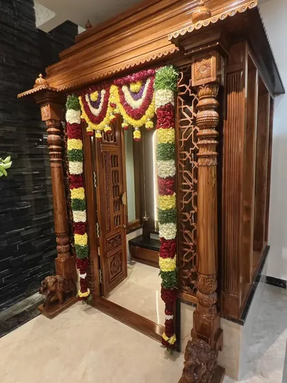 For a Gruhapravesam or housewarming, the pooja room is the heart of the home. We adorned this beautifully carved wooden pooja mandir with traditional floral garlands, creating a sacred and welcoming space for the ceremony.