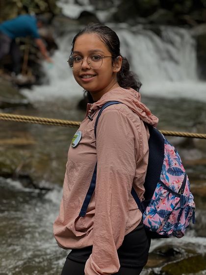 A young trekker smiling by a waterfall on the Netravathi trail. Our treks are designed to be safe and fun for all.