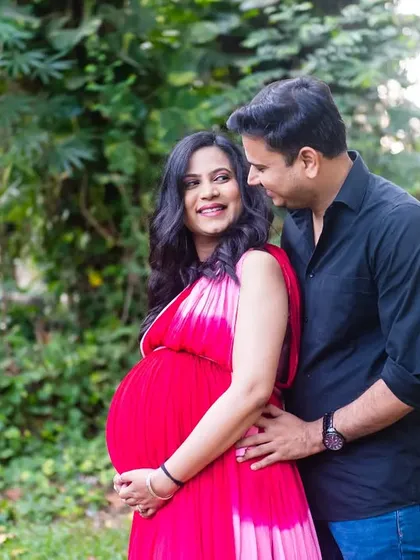 A classic, loving pose. The dad-to-be stands behind his partner, gently holding her, as they both look at each other with smiles.