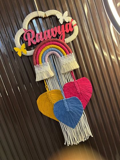 An angled view of the 'Raavya' nameplate, highlighting the 3D effect of the name and the different layers of the design, from the cloud to the hanging hearts.