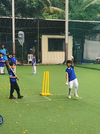 A young bowler in action on the turf pitch. Our training for junior players includes learning the fundamentals of both batting and bowling, ensuring a well-rounded introduction to cricket.