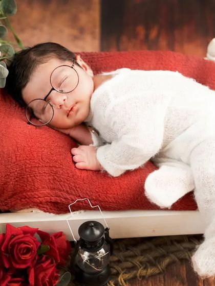 A handsome little newborn dreaming in his tiny bed. The little glasses add a touch of adorable personality to this sleepy shot.