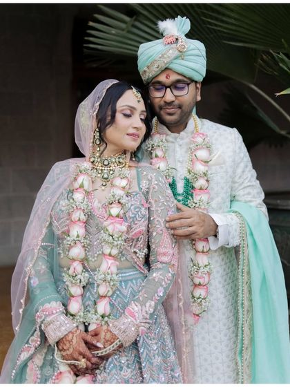 A beautiful portrait of the couple adorned with their varmala garlands. Their serene expressions and coordinated pastel outfits create a picture of elegance and togetherness.
