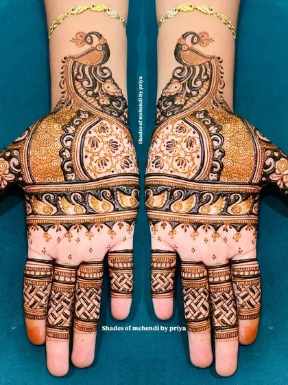 An example of intricate Indian mehendi with beautiful symmetry. This design features majestic peacocks and detailed patterns covering both hands, perfect for a bride who loves classic and elaborate henna art.
