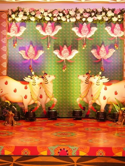 A divine stage for a baby shower, inspired by the Pichwai paintings of Nathdwara. The backdrop features sacred cows and lotus motifs, creating a traditional and artistic setting to welcome a new baby.