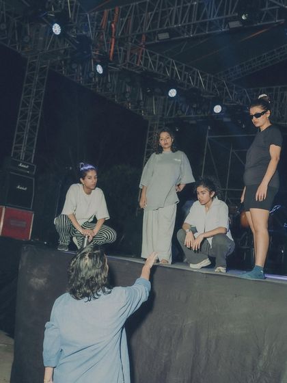 Directing the dancers on stage during a rehearsal, setting up the blocking and formations for the show.