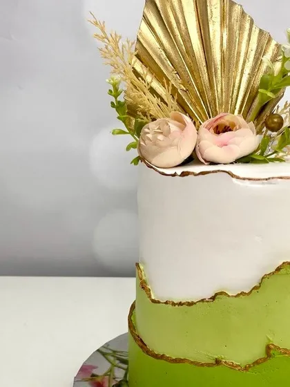 A close-up of the green textured cake, showing the gold-lined edge and the delicate floral arrangement.