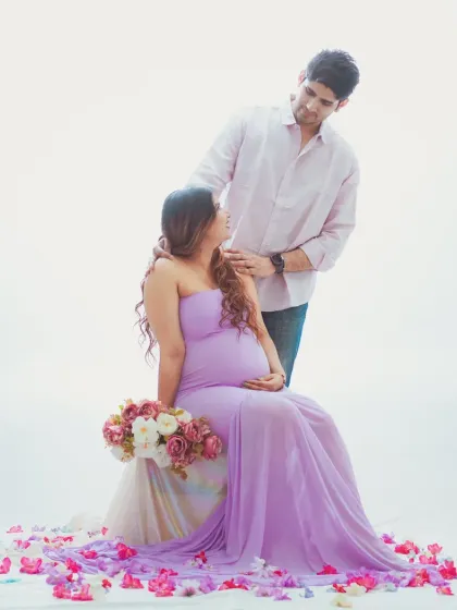 A romantic couple maternity shoot with a light and airy feel. The soft lavender gown and minimalist white background create a serene atmosphere, focusing on the connection between the expecting parents.