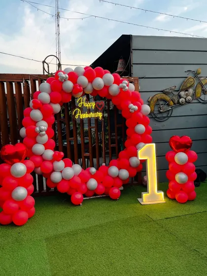 This wide shot shows the complete first-anniversary setup on an artificial lawn, featuring the circular balloon arch, light-up number, and matching balloon pillars.