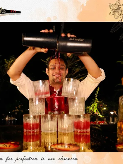 A bartender performs a layered pour, creating a visually impressive tower of cocktails. This flair move is not just for show; it's about creating multiple drinks efficiently with style.