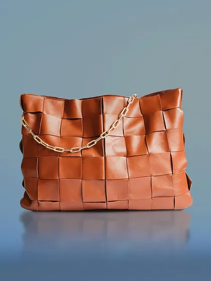 This shot captures the unique woven texture and gold chain detail of a leather handbag. I use careful lighting and composition to make fashion accessories look luxurious and desirable for high-end e-commerce stores.