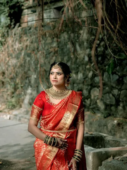 A thoughtful pose, showcasing the rich texture of the Banarasi silk saree. The makeup is kept classic, with a focus on flawless skin and defined eyes.