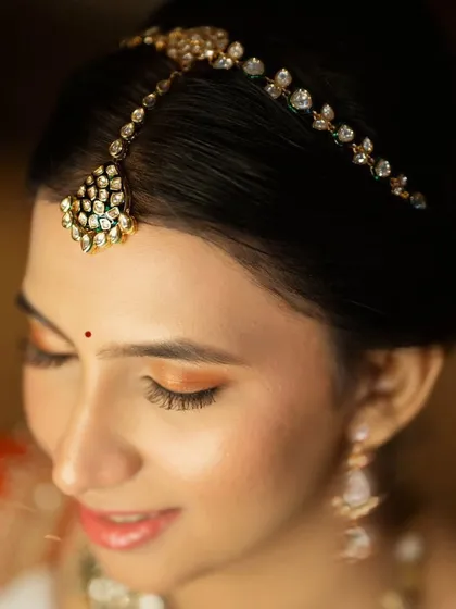 A detailed shot of the eye makeup, featuring a beautiful wash of orange shimmer that complements her red lehenga.