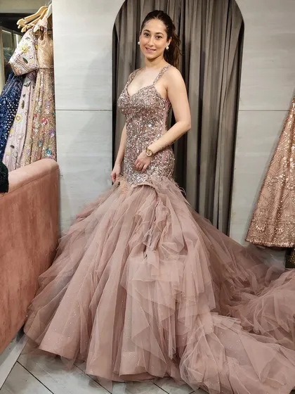 Which gown suited her better? This client is trying on a beautiful dusty pink fish-tail gown with a long, ruffled trail.