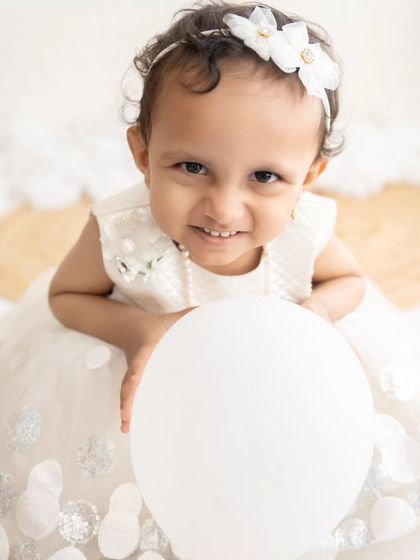 A beautiful close-up portrait of a toddler girl with a charming smile. The high-angle shot is very flattering.