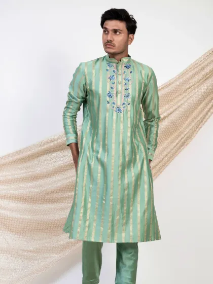 This striped mint green kurta offers a fresh and modern take on festive wear. The subtle gold stripes are complemented by delicate floral embroidery around the neckline.