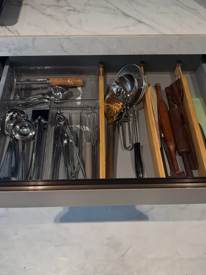 A utensil drawer with a mix of clear and bamboo dividers. This system separates everyday tools like whisks and peelers from specialized items like rolling pins.