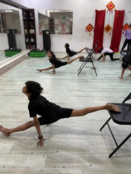 Our young dancers using chairs to assist with split stretches, a technique that helps improve alignment and deepen the pose safely.