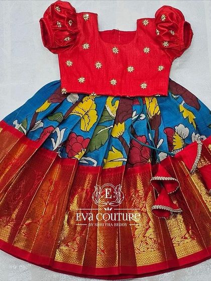 A bright and cheerful Kalamkari lehenga. The red blouse is paired with a blue floral print skirt with a wide red and gold border.