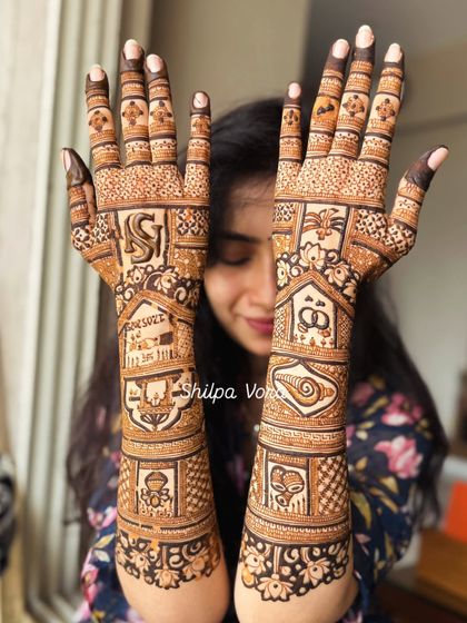 Full bridal mehndi with personalized elements. This design includes the couple's initials, wedding rings, and other symbols that tell their story, covering the hands and arms completely.