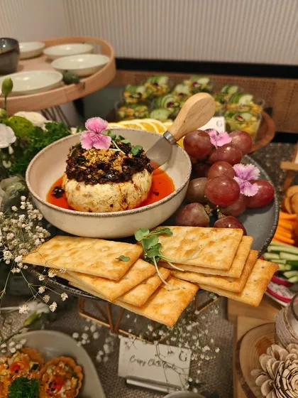 A serving of our Crispy Chilli Tofu, presented with crackers and garnished with an edible flower. This dish offers a delightful combination of textures and flavors.