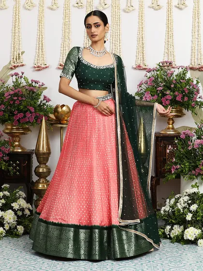Another elegant pose in the coral and green lehenga, highlighting its graceful silhouette.
