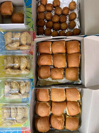 Party snacks packed and ready to go, including mini burgers, cheese balls, and ghugra.