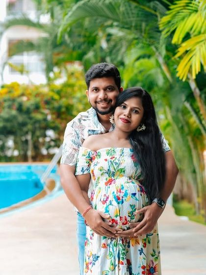 A classic couple's pose during a poolside maternity shoot. The lush green background and relaxed outfits create a beautiful, natural portrait.