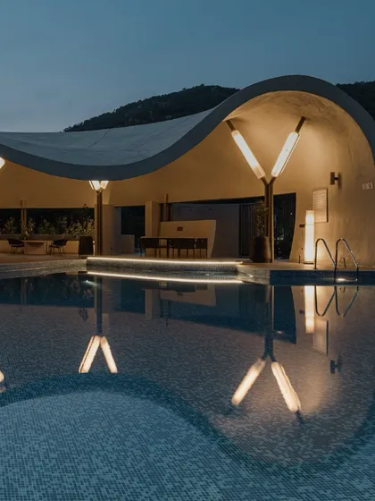 A close-up night shot of the Aqua Pool & Spa, highlighting the reflection of the architectural lighting on the pool's surface.